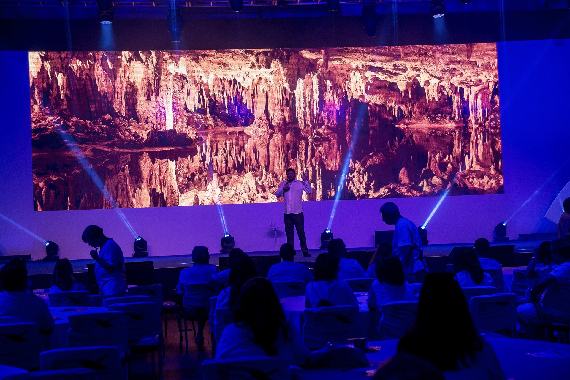 Fernando Palacios presenting in a darkened room lit with theatrical lighting